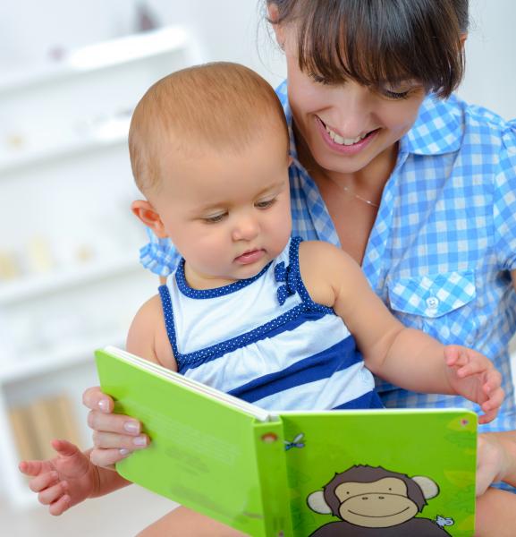 Woman with a baby on her lap reading a picture book.